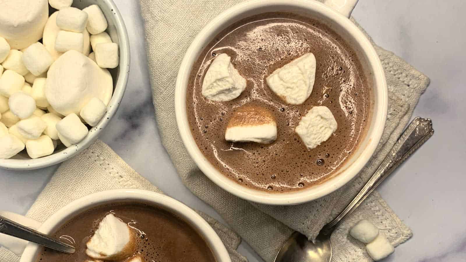 Two bowls of hot chocolate with marshmallows on top.
