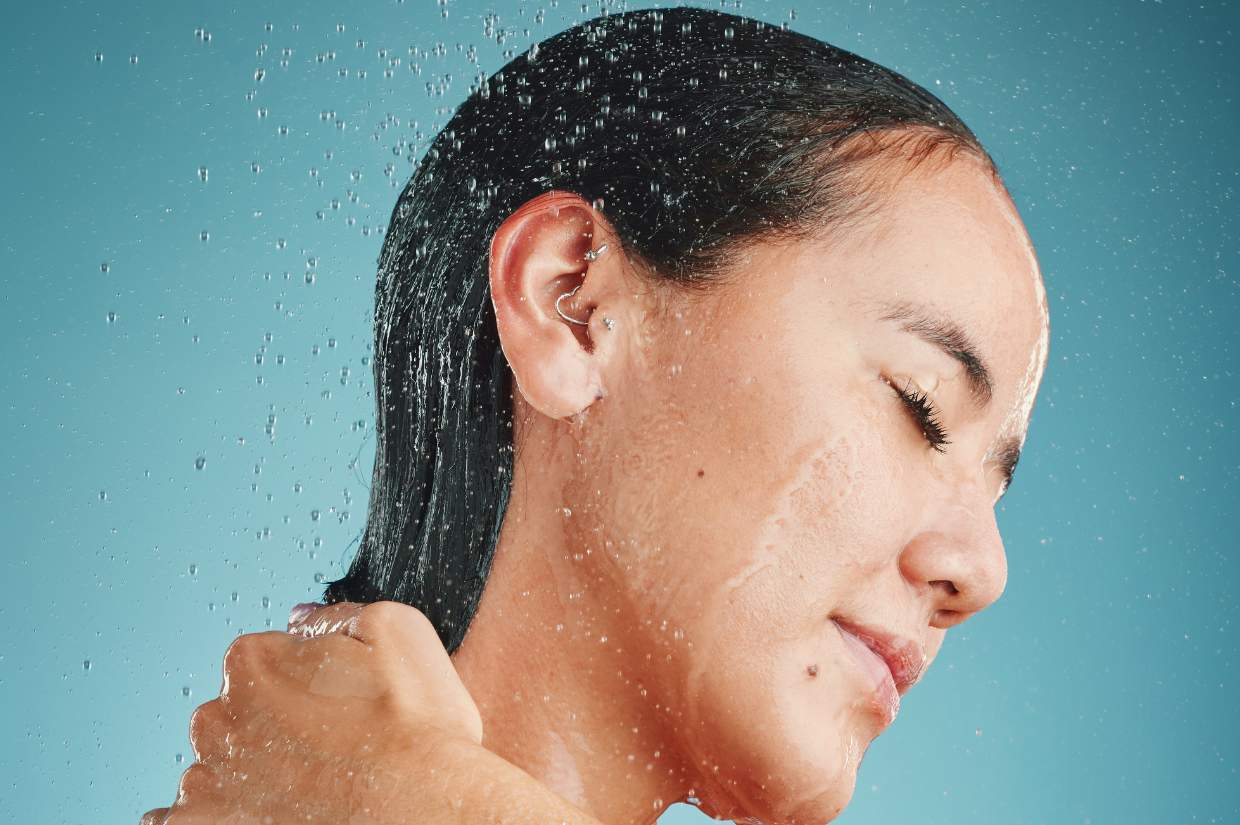 A woman is showering her hair.