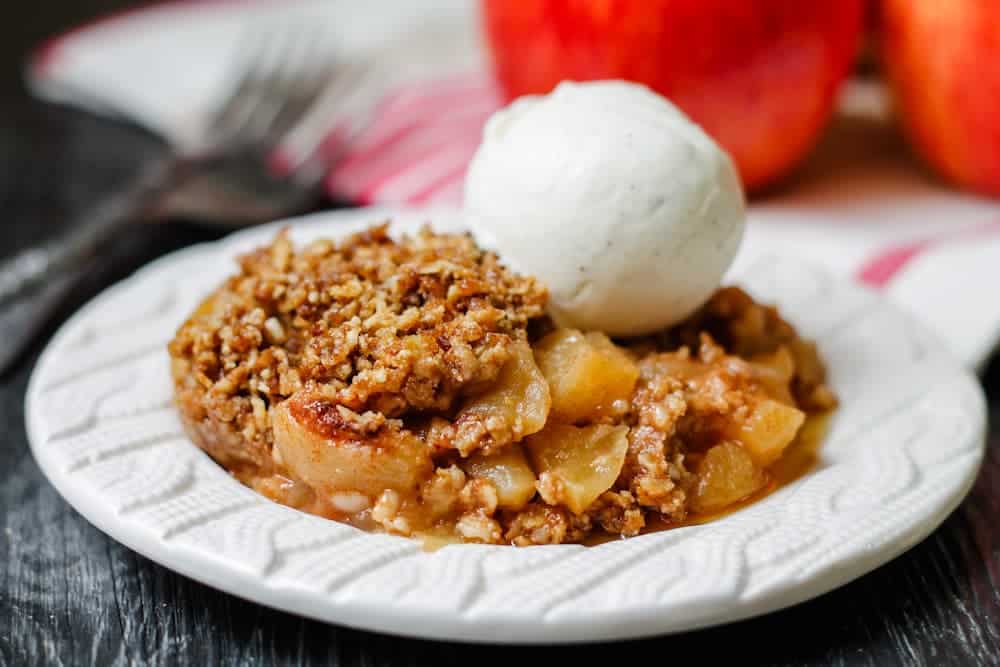 A plate of apple crumble topped with vanilla ice cream.