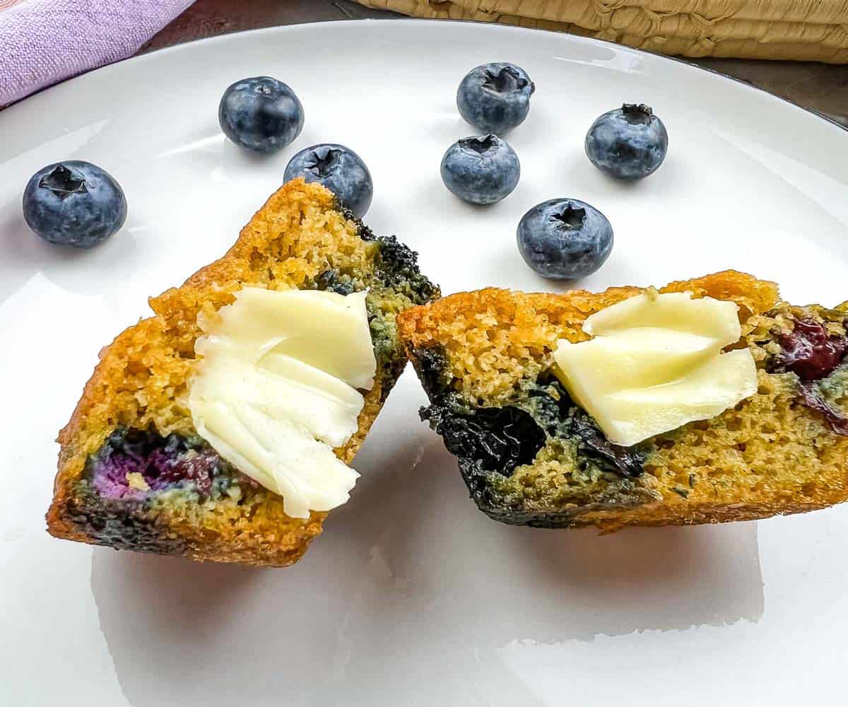 Blueberry muffins with butter and blueberries on a plate.