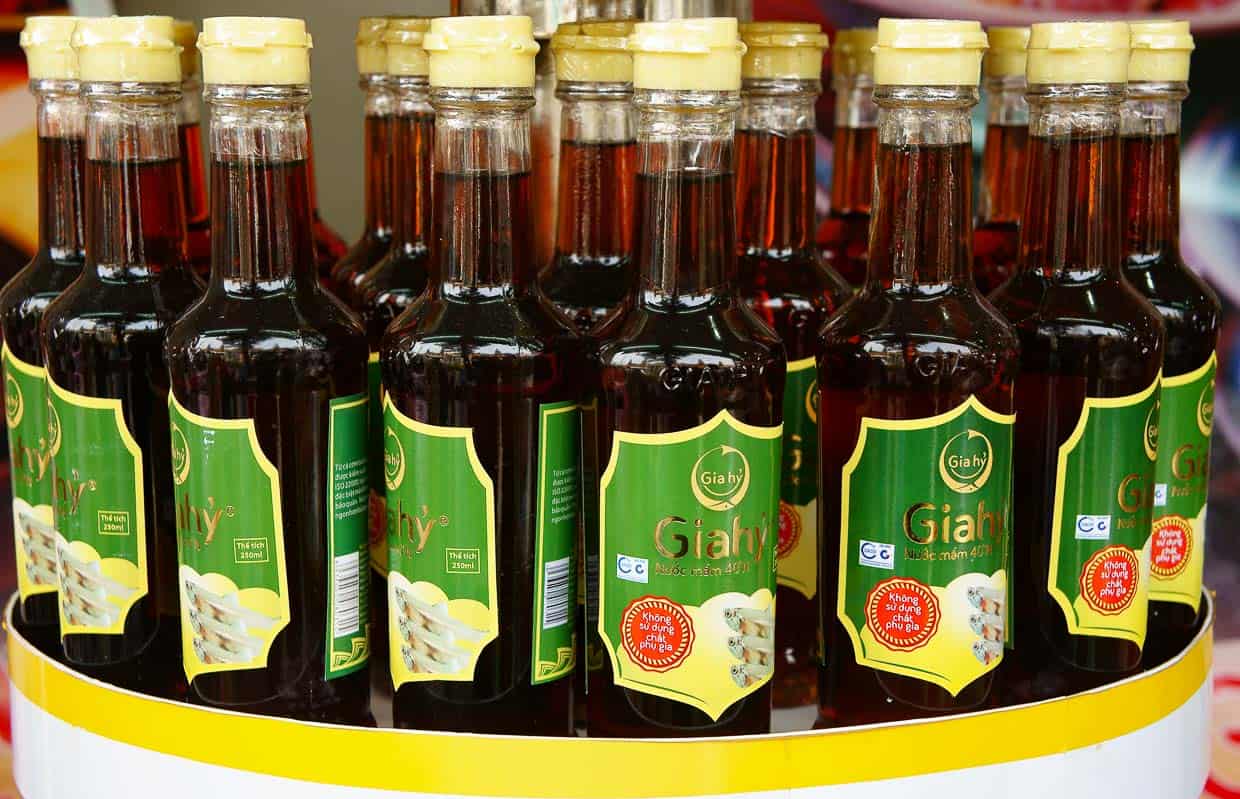 A group of bottles of fish sauce sitting on a stand.
