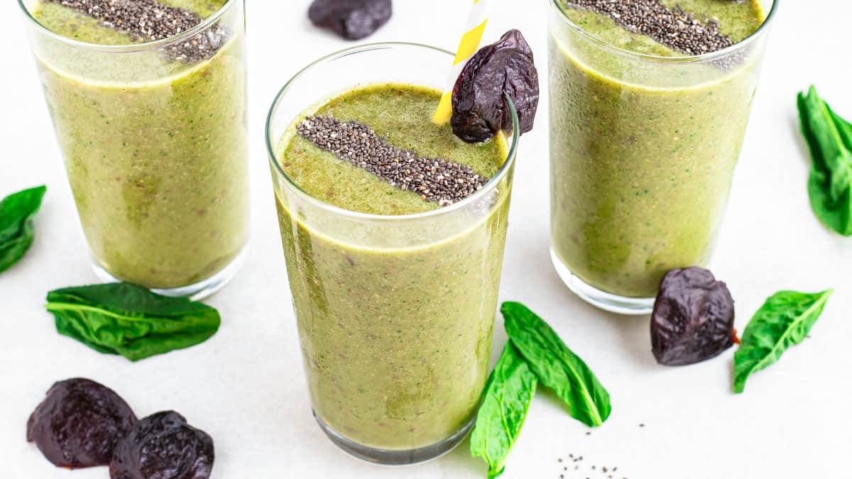 Three glasses of green prune smoothie with chia seeds.