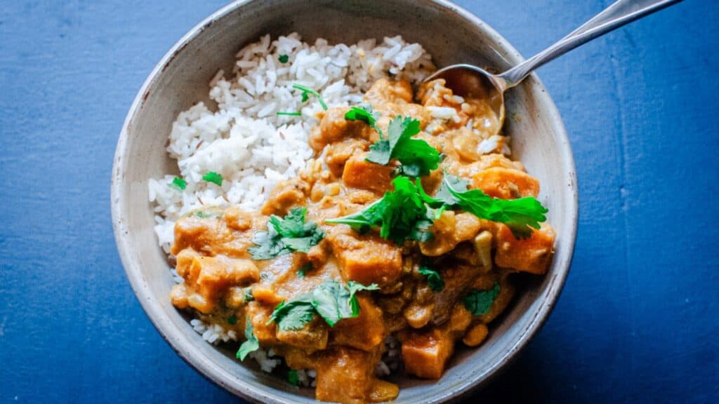 A bowl of curry with rice and cilantro.