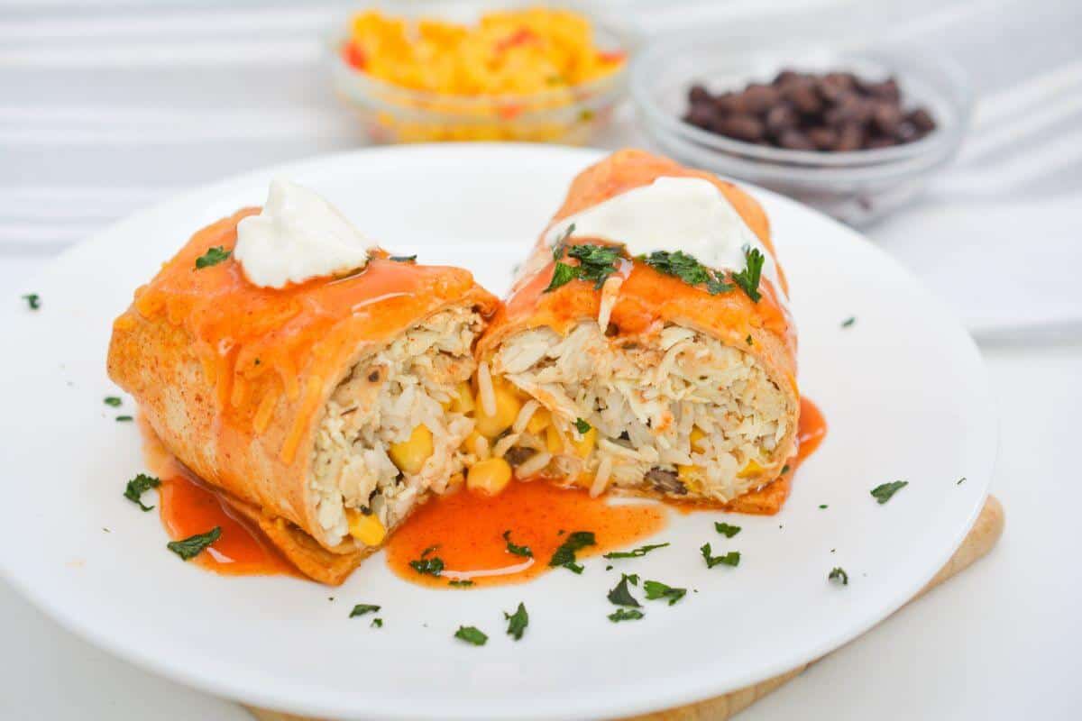 Chicken wet burrito with salsa and sour cream on a white plate.
