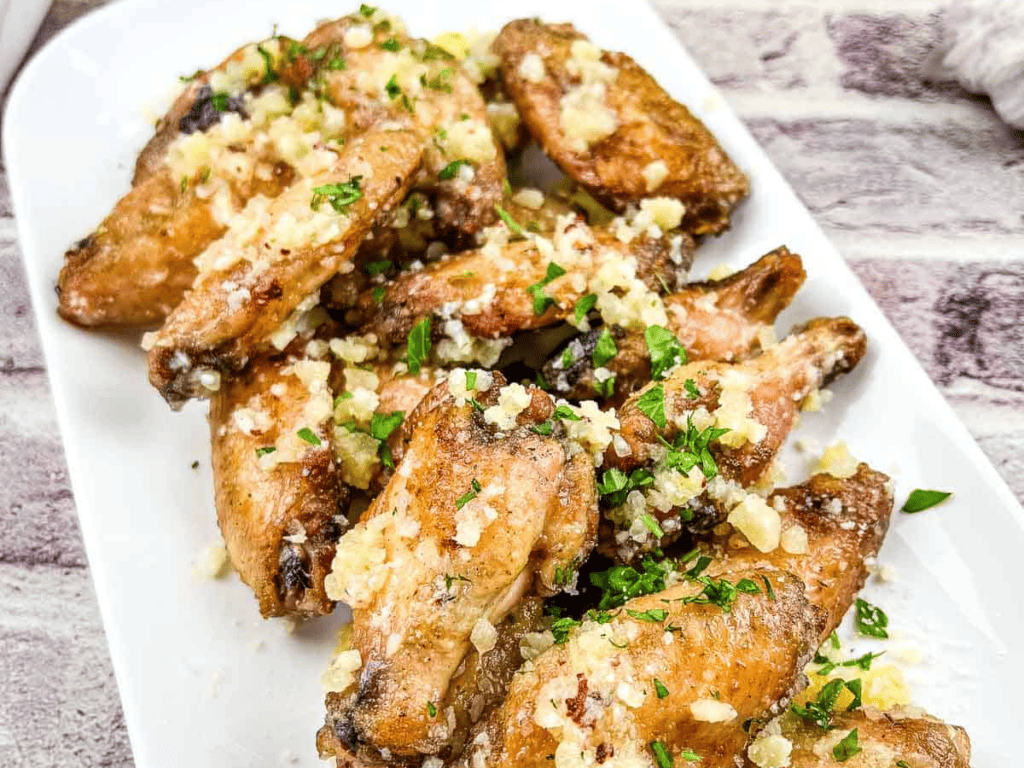 Chicken wings with garlic and parsley on a white plate.