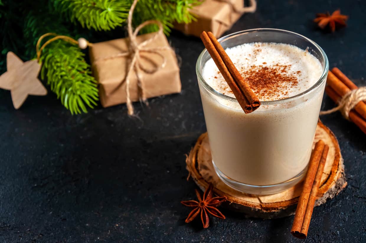 A drink with cinnamon and cinnamon sticks on a black background.