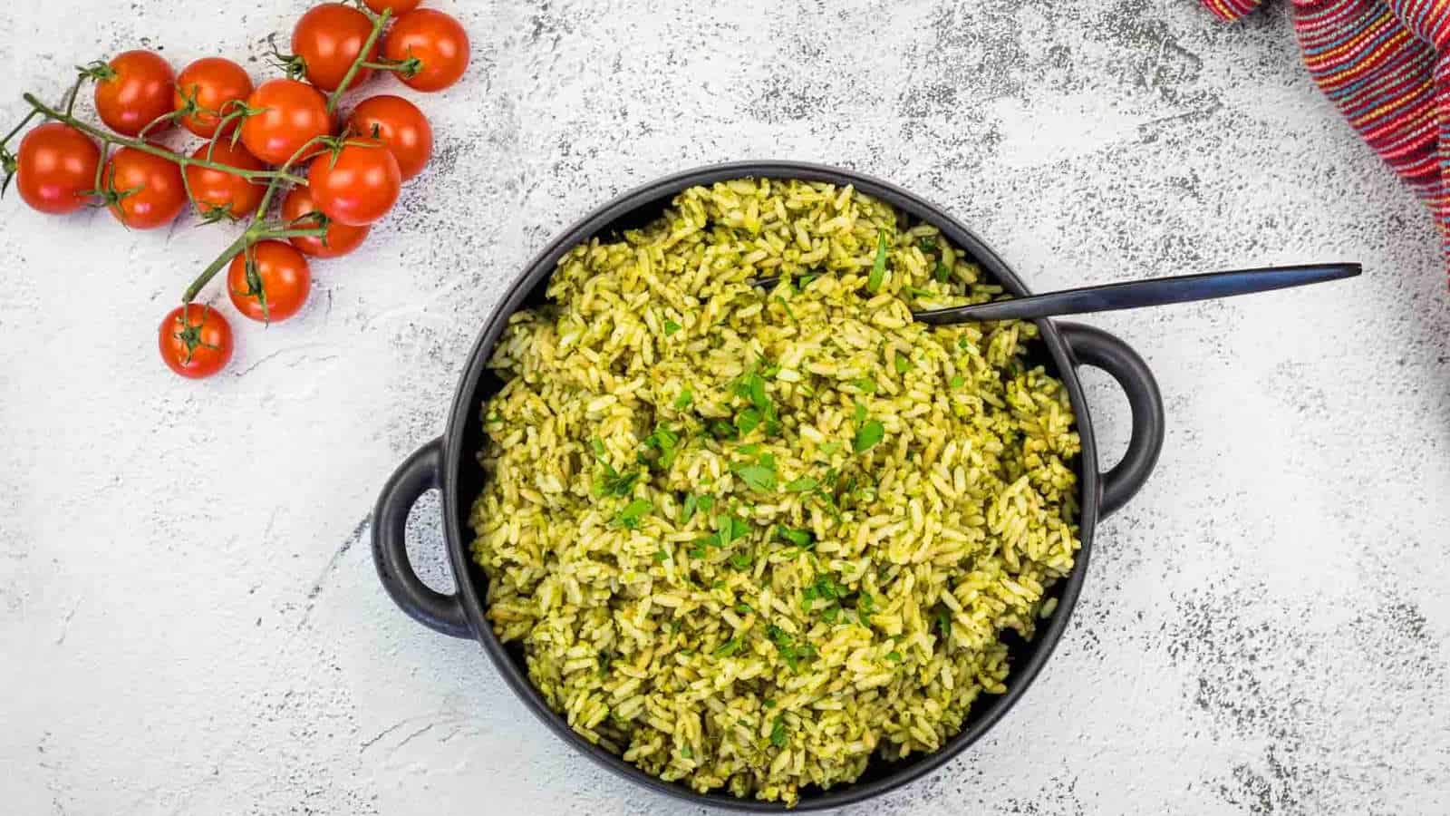 Arroz Verde rice in a black pan with tomatoes and herbs.