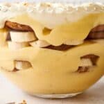 Banana pudding in a bowl with whipped cream and bananas.