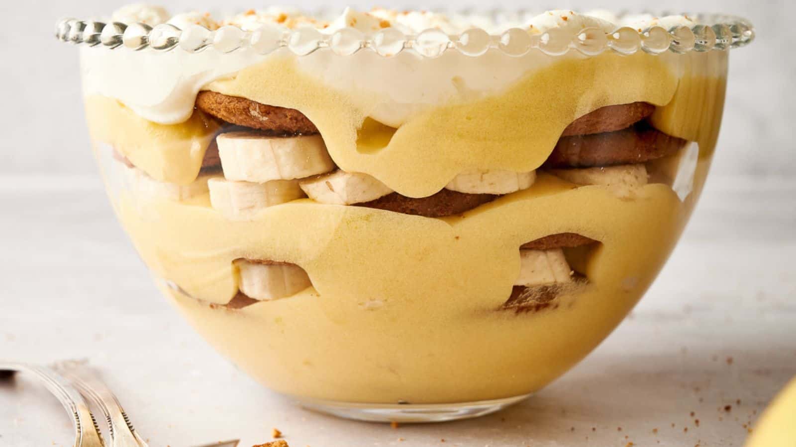 Banana pudding in a bowl with whipped cream and bananas.