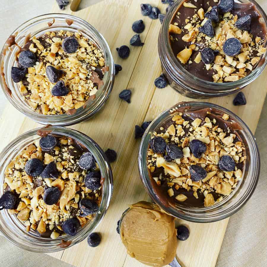 Four jars of chocolate pudding with peanut butter and chocolate chips.