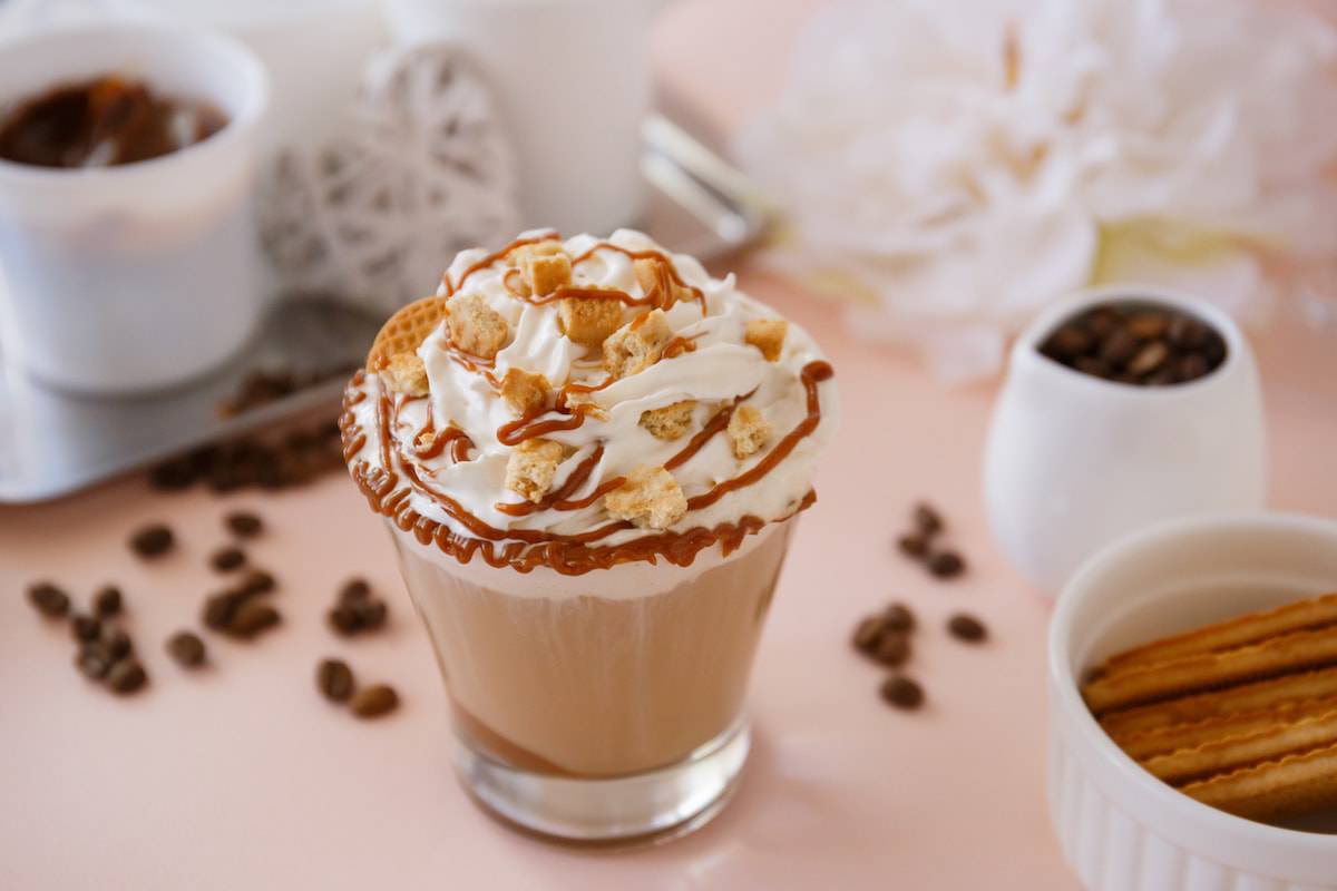 A cup of coffee with whipped cream and cinnamon sticks topped with Nigerian Jollof Rice.