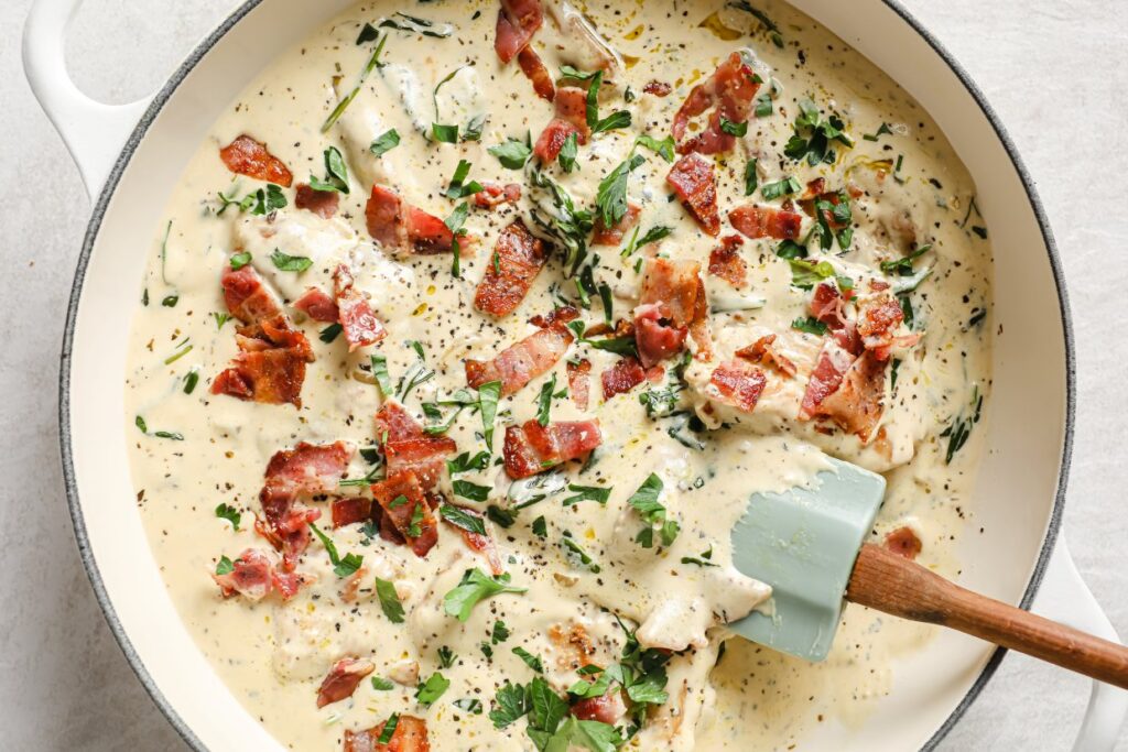 A pan with chicken, spinach and bacon in it.
