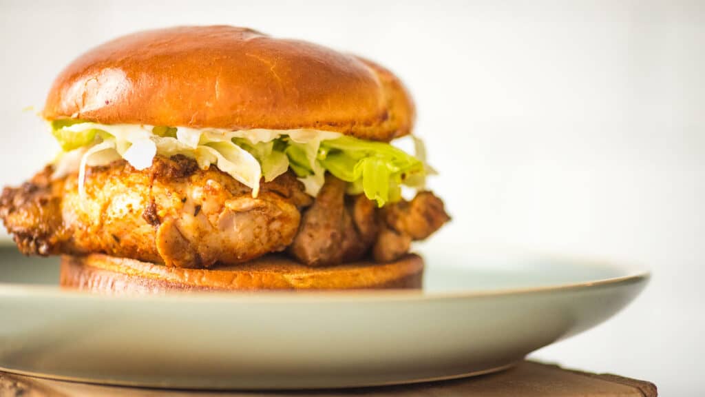 A blackened chicken sandwich is sitting on a plate.