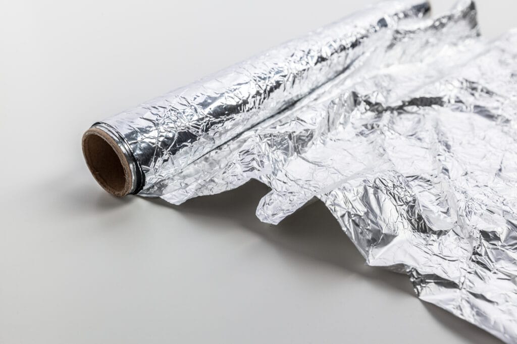 A roll of aluminum foil on a white surface.