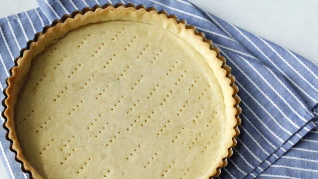 A pie crust on a blue and white striped towel.