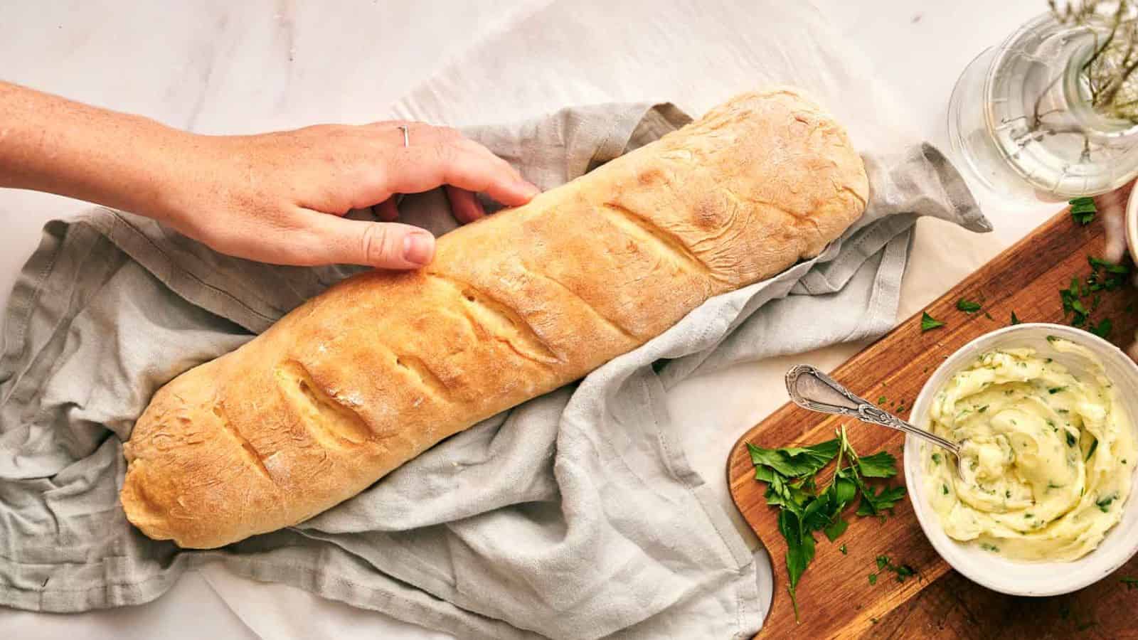 A person is holding French bread.