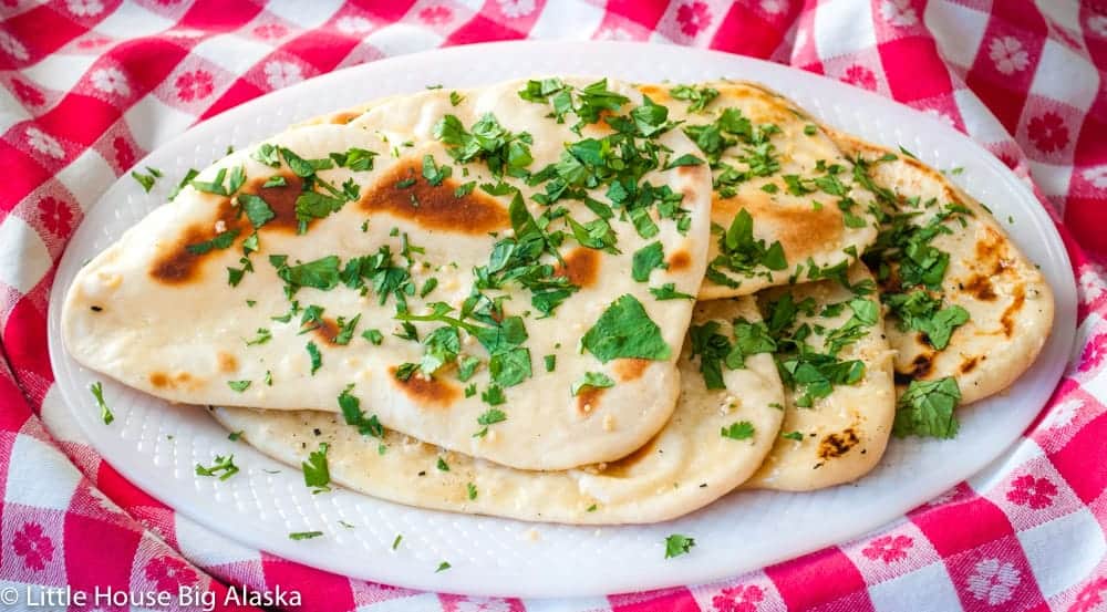 Naan bread with chopped cilantro on a white plate.