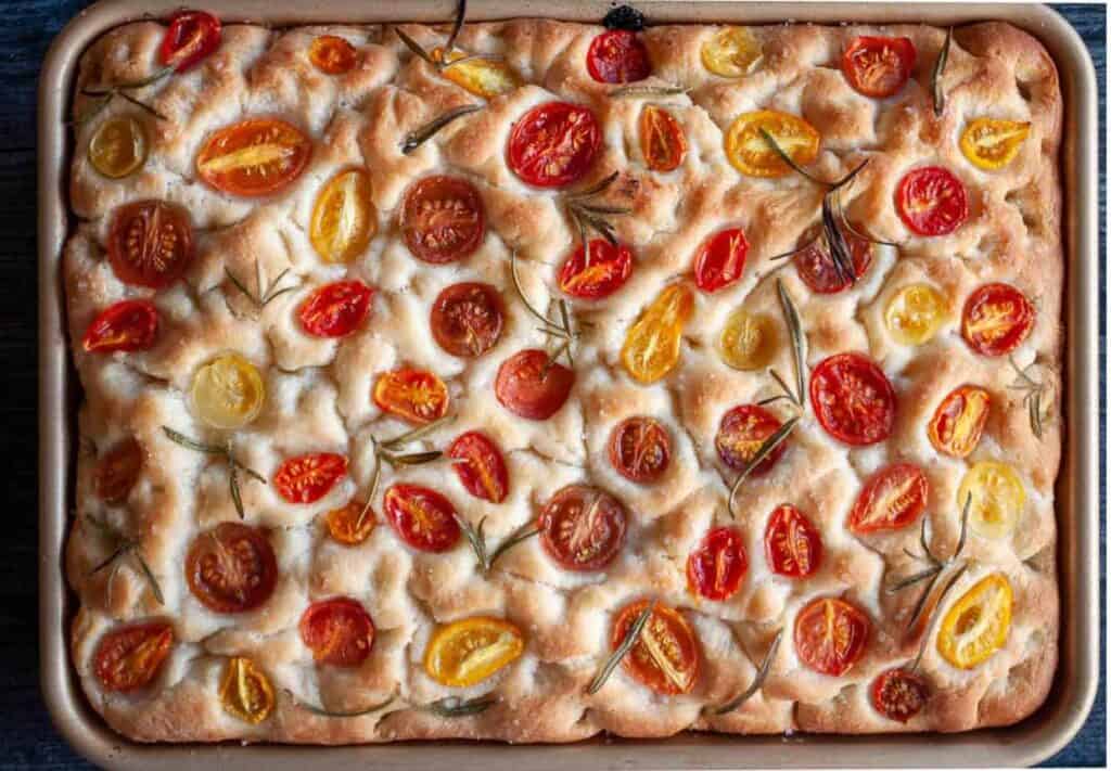 A tray of food with tomatoes on top.
