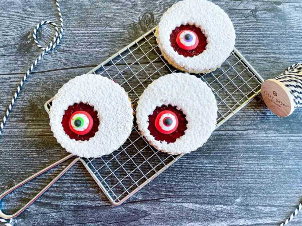 Three cookies with red eyes on a cooling rack.