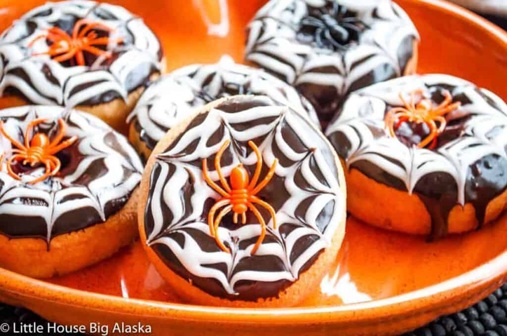 Halloween spider donuts on an orange plate.