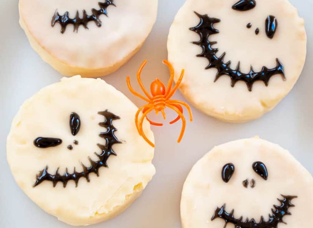 A plate of cookies decorated with jack o lantern faces and spiders.