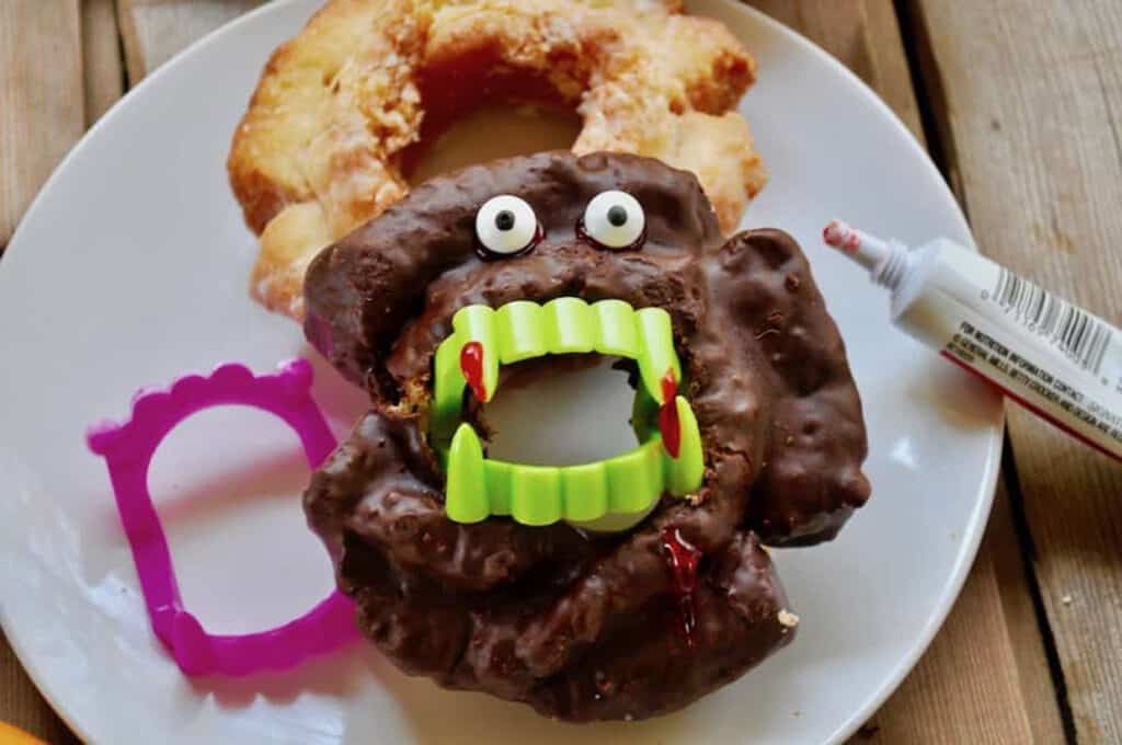 A plate with a doughnut with a monster face on it.