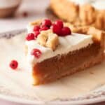 A slice of pumpkin pie on a plate with cranberries.