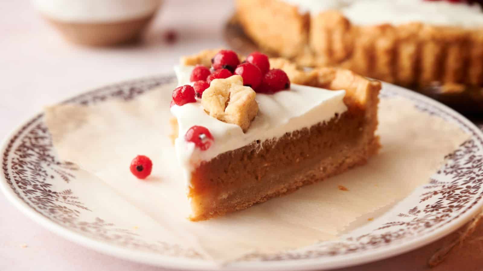 A slice of pumpkin pie on a plate with cranberries.