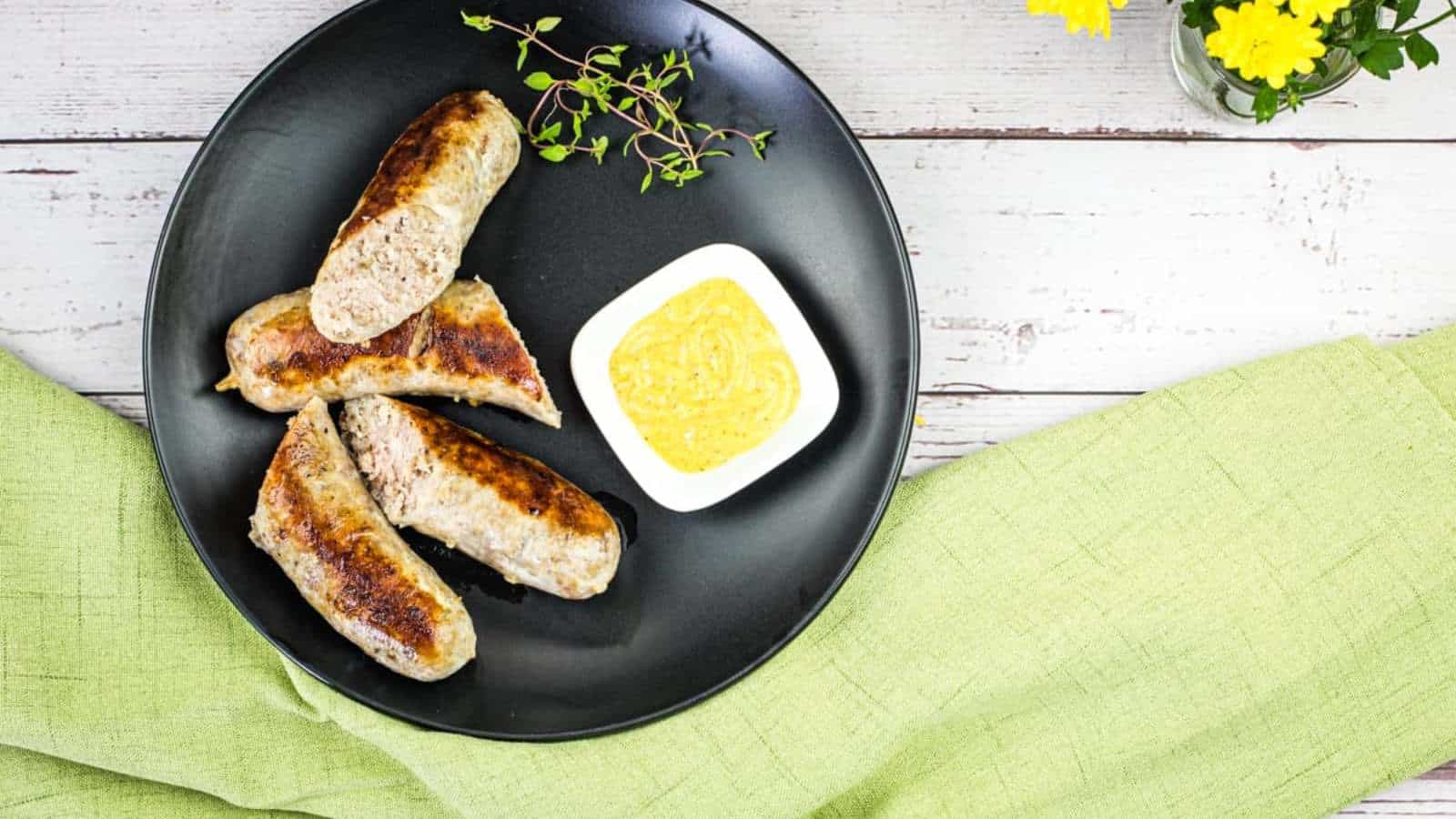 Sous Vide Sausage with mustard sauce on a black plate.