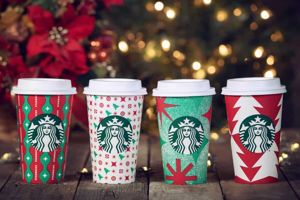 Four starbucks cups with christmas decorations on them.