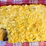 A casserole dish with shredded cheese and a wooden spoon.