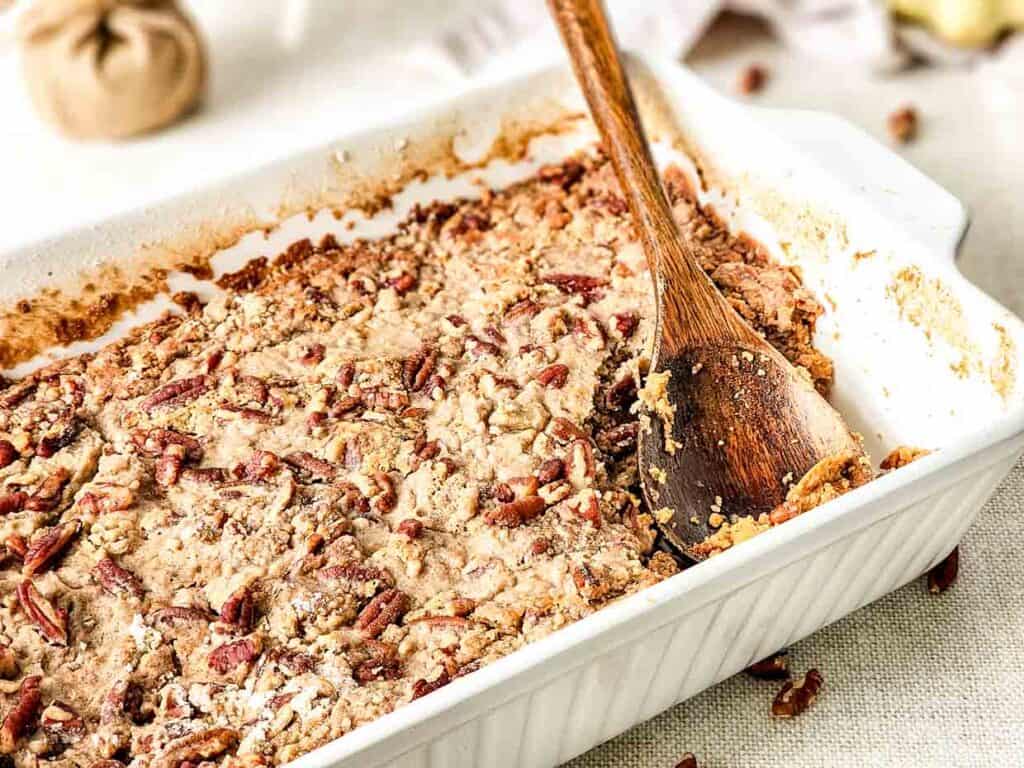 A casserole dish with a wooden spoon and a sweet potato dump cake.