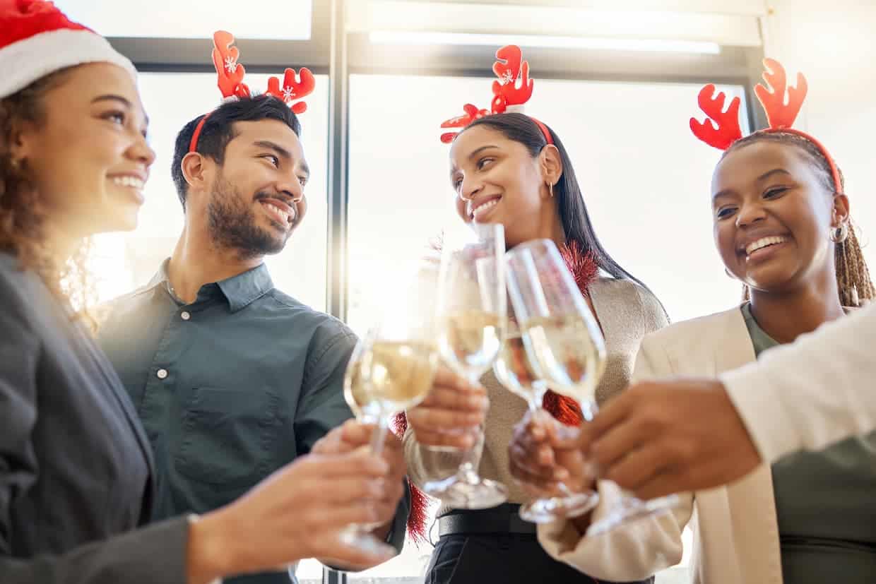 A group of people in christmas hats toasting with champagne glasses.