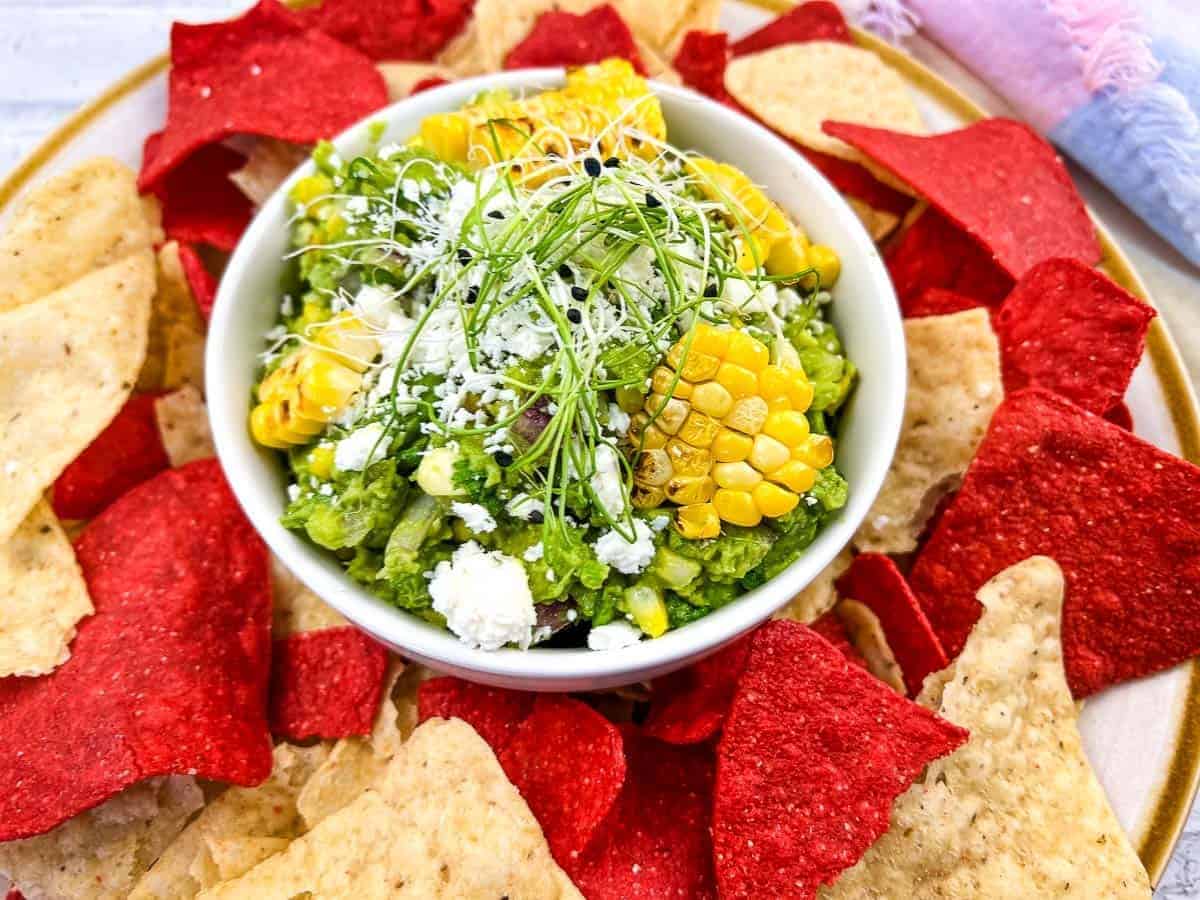 Corn guacamole with tortilla chips on a plate.