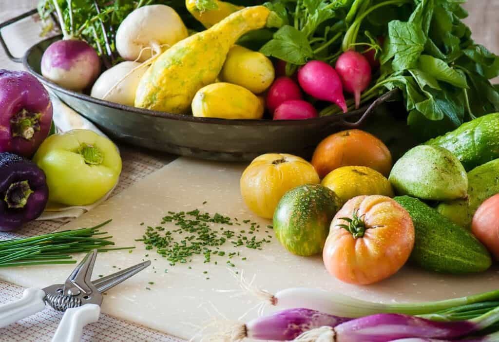 Fresh fruits vegetables on a cutting board.