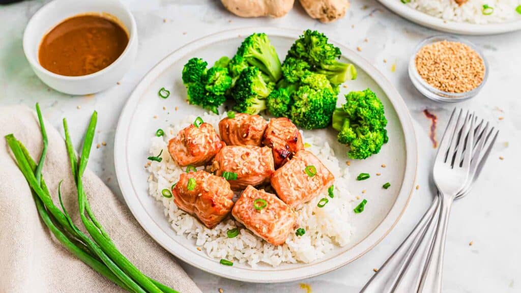 A plate with air fryer salmon bites, rice, broccoli and sauce on it.