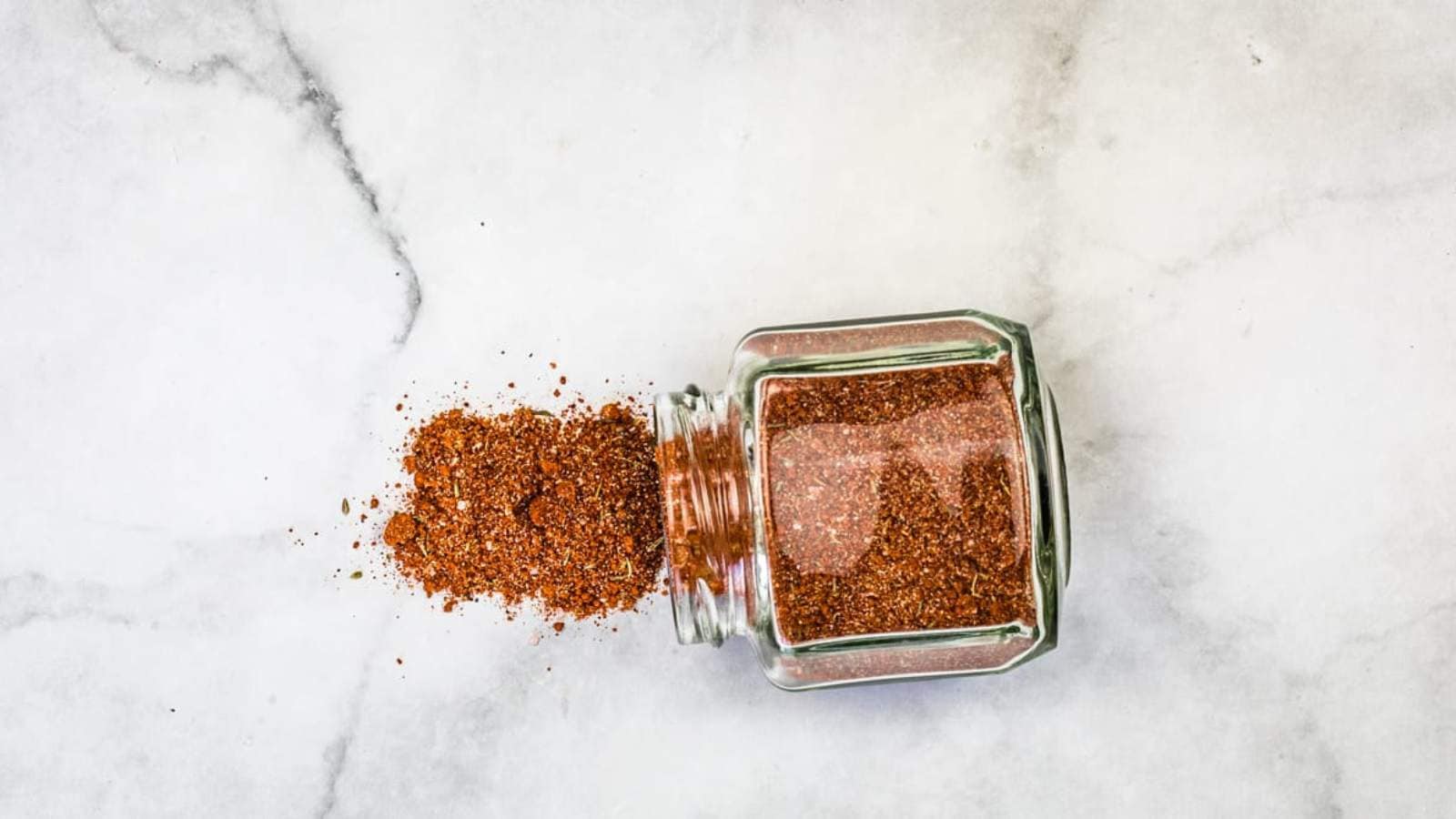A jar of pork rub on a marble table.