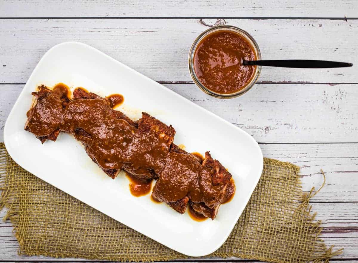 Ribs with bourbon BBQ sauce on a white plate.
