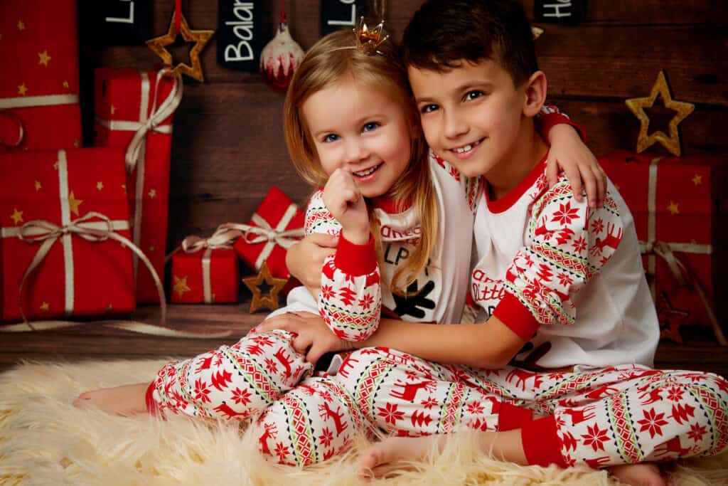 Two children in matching Christmas PJs posing for a photo.