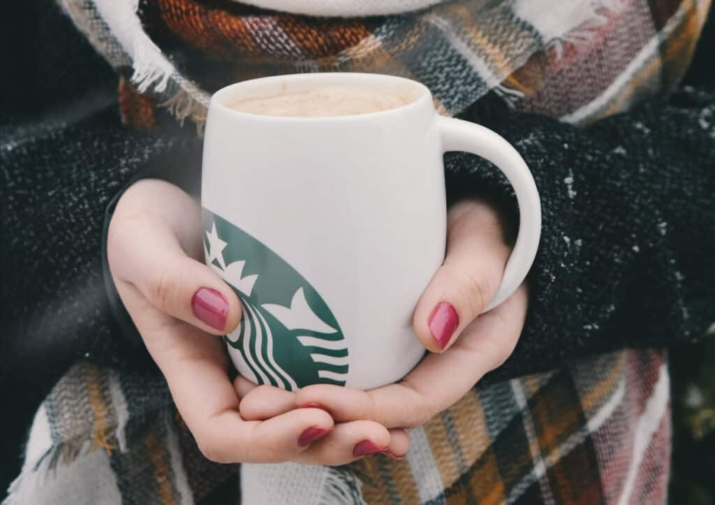A woman holding a starbucks coffee cup.