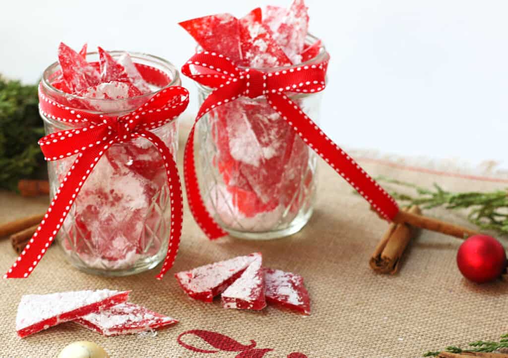 Two jars of cinnamon candy with red ribbons.