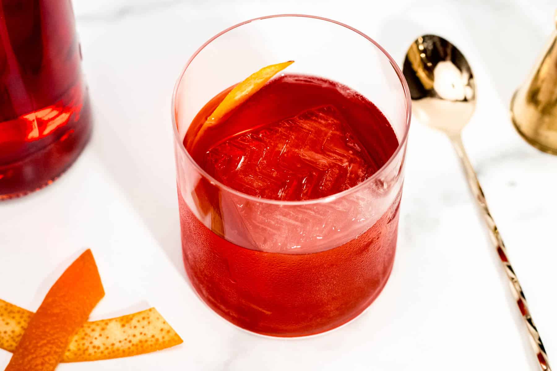 A glass with a Classic Negroni and orange peels.