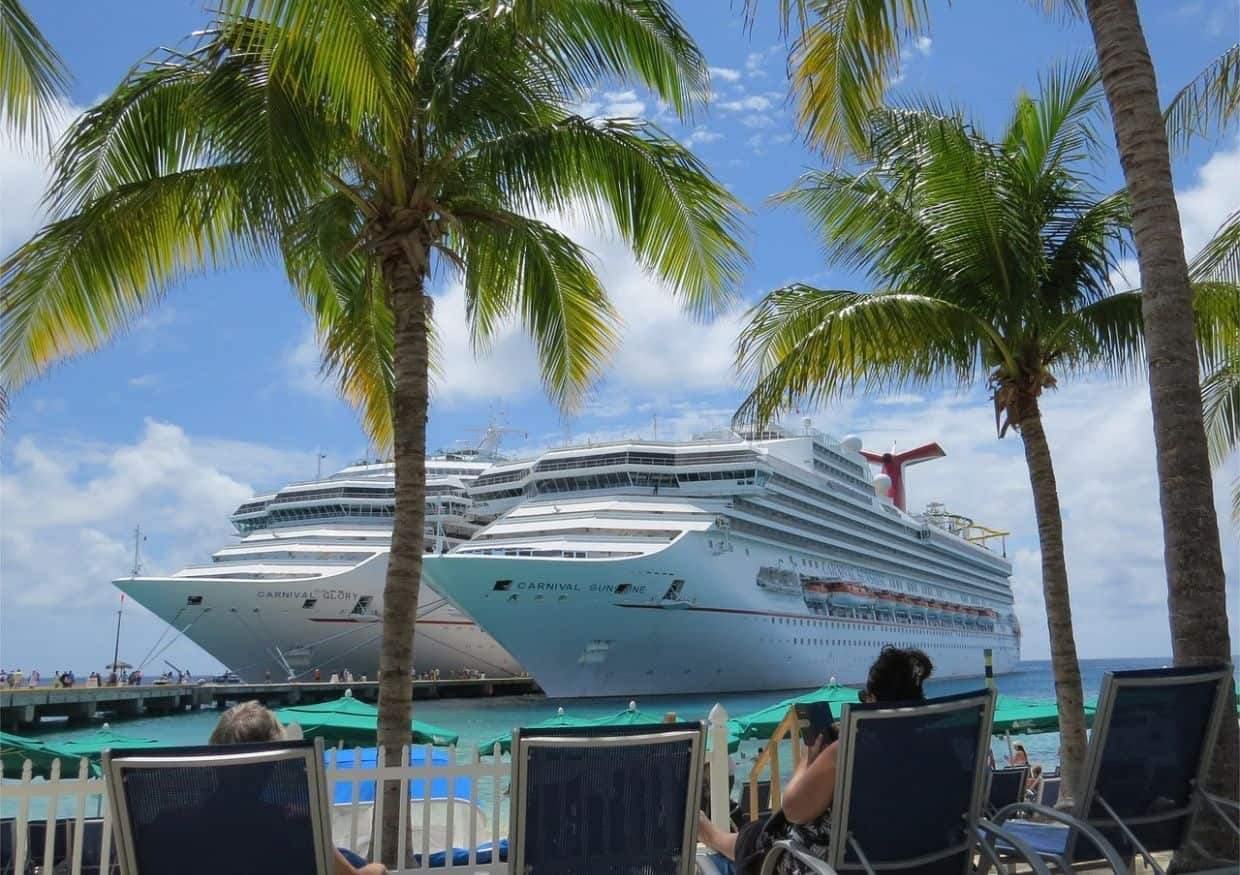 Two cruise ships docked at a beach in the caribbean.