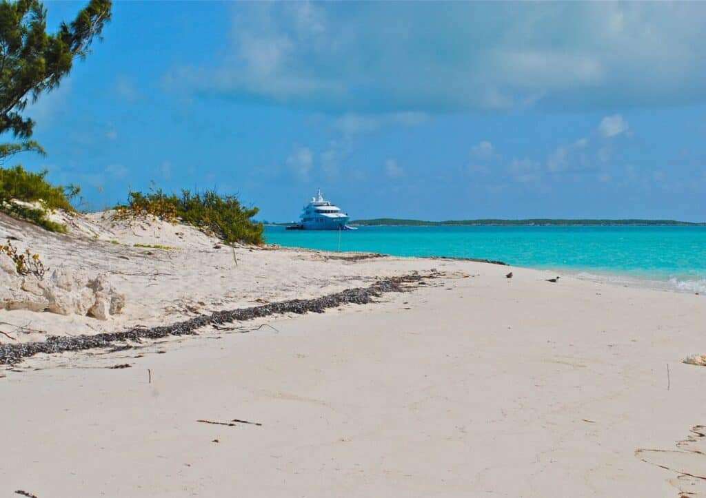 A white sand beach with a boat in the water.