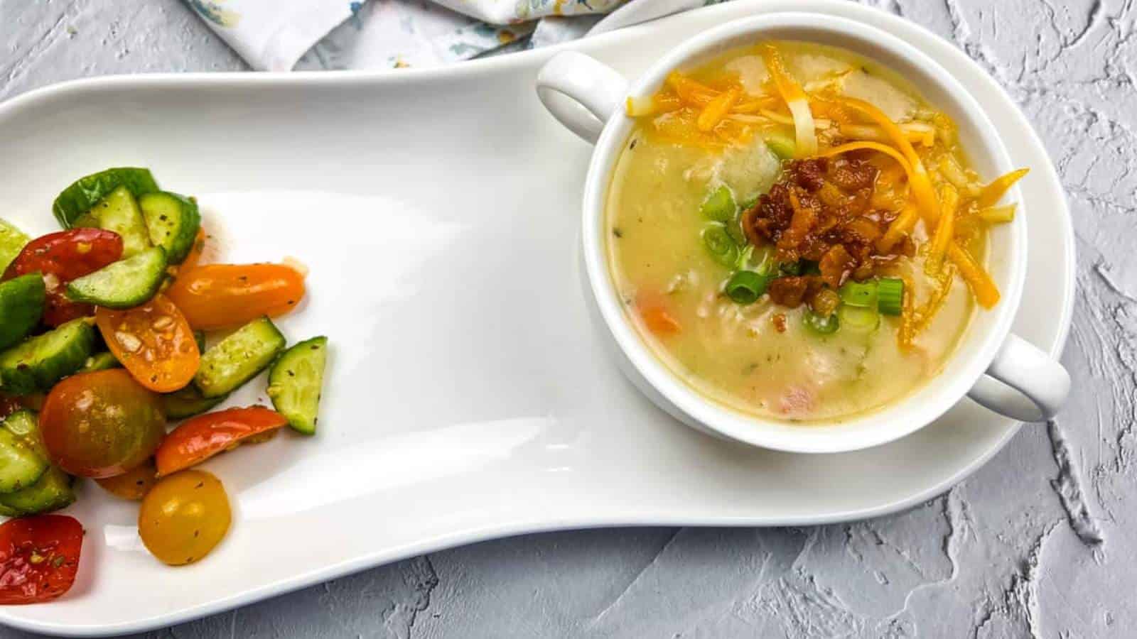 A white plate with fully loaded baked potato soup and vegetables on it.