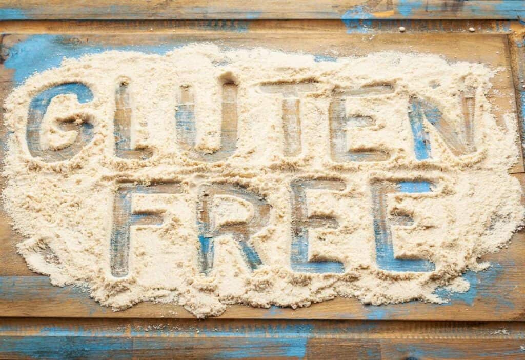 The word gluten free spelled out in sand on a wooden background showcasing gluten free.