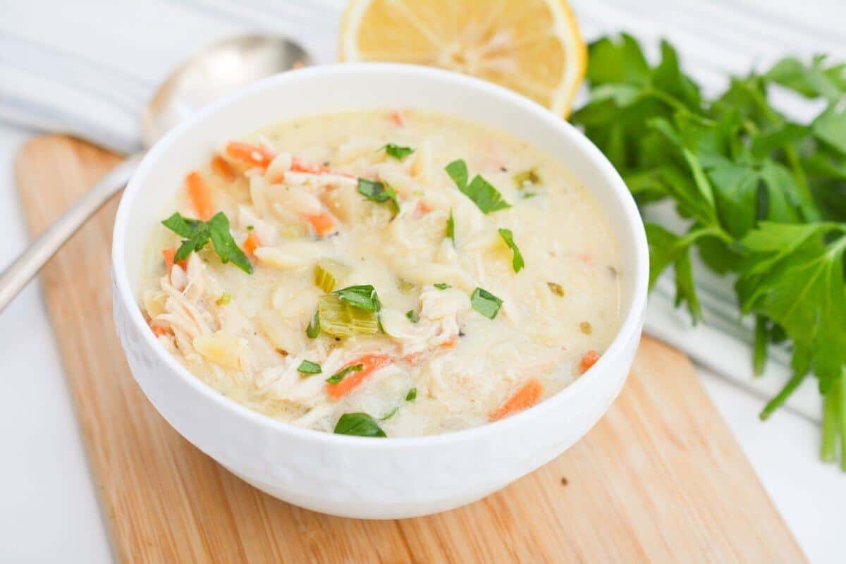 Lemon chicken soup in a white bowl with lemon slices.