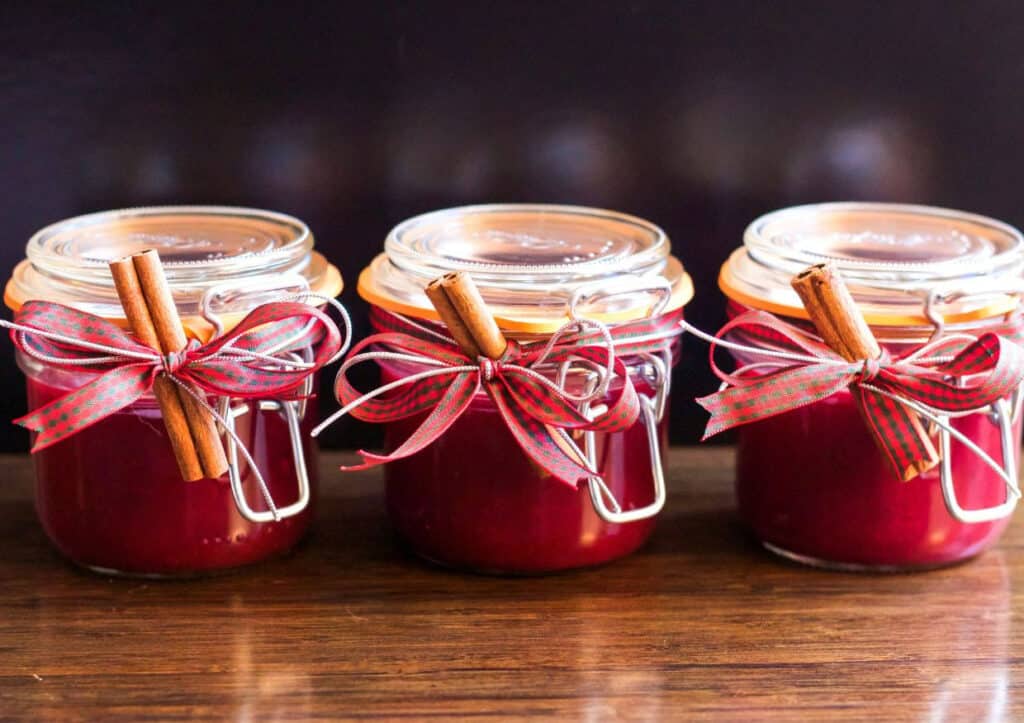 Three jars of cranberry chutney with cinnamon sticks.
