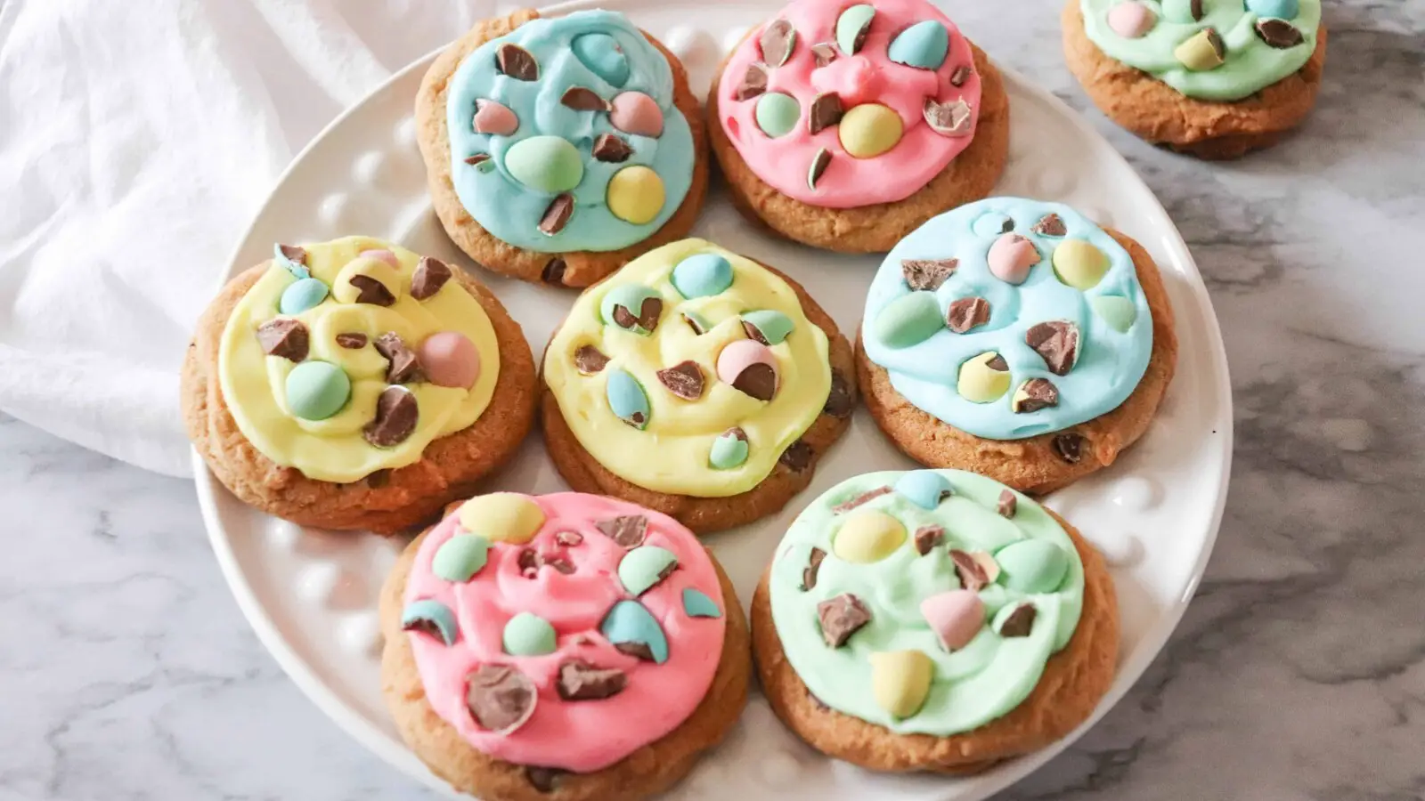 Mini egg cookies on a white plate with colorful icing.