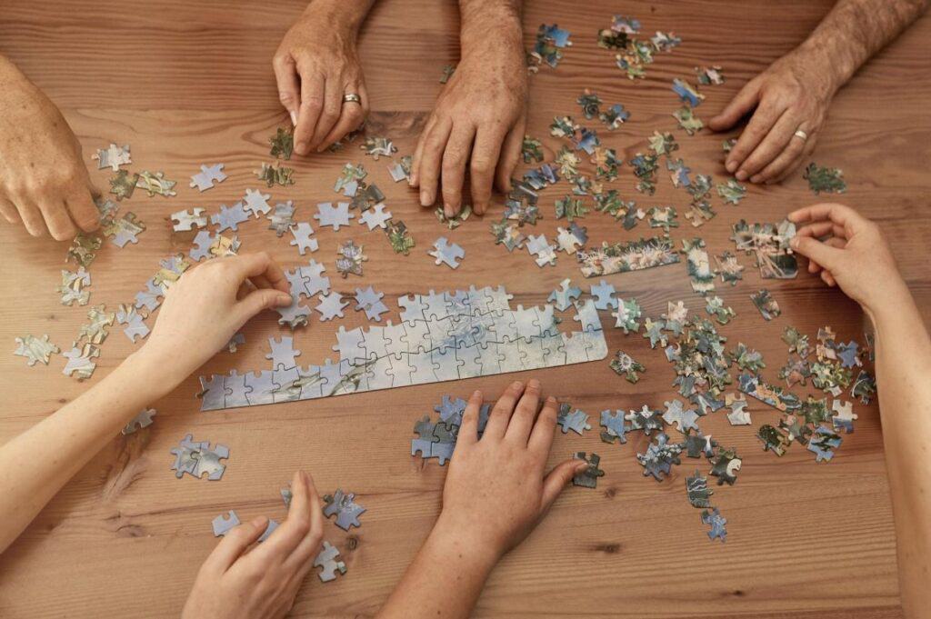 A group of people finding natural stress relief by putting together a jigsaw puzzle.